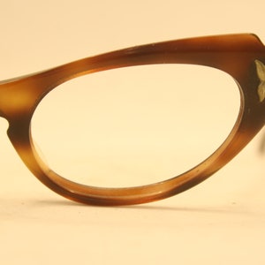 May include: A pair of brown tortoiseshell cat-eye glasses with gold accents on the temples.