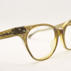May include: A pair of vintage cat-eye glasses with a brown tortoiseshell frame and clear lenses. The frame is decorated with rhinestones.