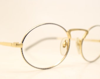 Peut inclure: Lunettes ovales avec une fine monture en métal doré et des verres transparents.