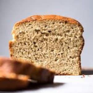 May include: A close-up of a sliced loaf of bread. The bread is light brown and has a slightly crumbly texture.