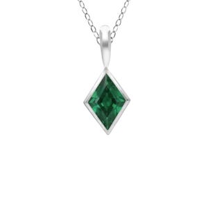 Puede incluir: Un collar con colgante de plata que presenta una piedra preciosa de color verde oscuro facetada en forma de cometa, engastada en un bisel de plata liso. El colgante cuelga de una delicada cadena de plata con un diseño geométrico limpio.
