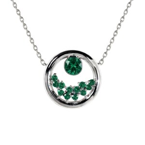 Può includere: Una collana color argento con un ciondolo circolare. Il ciondolo contiene una singola pietra preziosa verde rotonda nella parte superiore e un gruppo di pietre verdi rotonde più piccole disposte a mezzaluna nella parte inferiore interna.