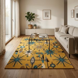 May include: A rectangular area rug featuring a mustard yellow background with a repeating pattern of blue, grey, and white starbursts, geometric lines, and circular shapes. The rug is positioned on a wooden floor in a living room setting.