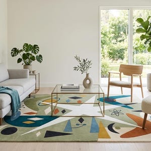 May include: A rectangular area rug featuring a sage green background with a large white star and various geometric shapes in navy blue, orange, yellow, and black. The design includes abstract motifs like boomerangs, circles, and lines.