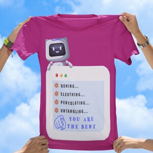 Könnte beinhalten: Ein magentafarbenes Kurzarm-T-Shirt mit einer Grafik eines kleinen Roboters über einer Computerfenster-Oberfläche. Der Text lautet: HONING, SLEUTHING, PERCOLATING, UNTANGLING und YOU ARE THE BEST, begleitet von einem Symbol eines zeigenden Fingers.