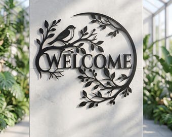 May include: A black metal wall sign featuring the word WELCOME in capital letters, integrated into a circular frame decorated with leafy branches and a small bird perched on a branch, creating a detailed silhouette against a light surface.