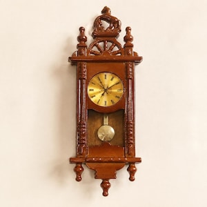 May include: A brown wall clock with a glossy finish, featuring a circular gold face with black Roman numerals. The clock has a decorative top with a horse figure, vertical side pillars, and a visible pendulum swinging in the lower section.
