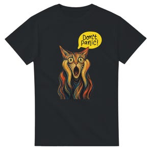Peut inclure: Un t-shirt noir à manches courtes orné d'une illustration expressive et colorée d'un chat aux yeux écarquillés et à la bouche ouverte, rappelant un style pictural célèbre. Au-dessus du chat, une bulle jaune contient le texte Don't panic!