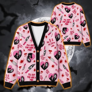 May include: A light pink V-neck button-down cardigan featuring a repeating pattern of black and white ghost masks inside pink hearts, silver knives, and red blood splatters. The text "I'LL GUT YOU LIKE A FISH" is printed in black on the fabric.