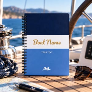 Könnte beinhalten: Ein spiralgebundenes Notizbuch mit einem dreifarbigen Einband aus dunkelblauen, weißen und hellblauen horizontalen Abschnitten. Der weiße Bereich zeigt den goldenen Schriftzug Boat Name, während der hellblaue Bereich den Text YOUR TEXT und ein weißes Logo enthält.