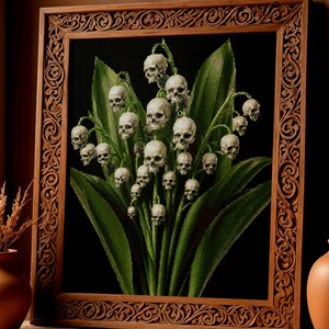 May include: A framed wall art piece featuring a dark background with a cluster of green lily of the valley leaves and stems. Instead of flowers, the stems are topped with numerous small, detailed white human skulls in a botanical arrangement.
