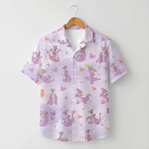 May include: A short-sleeve button-down shirt in a light purple hue featuring an all-over print of a purple dragon character in various poses, interspersed with small orange and purple mouse-ear silhouettes and four-pointed star accents.