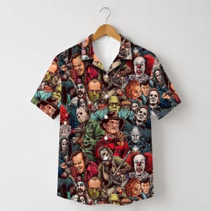 May include: A short-sleeve button-down shirt featuring an all-over print of various horror movie characters, including figures with red, green, and brown tones. The shirt has a classic collar, a front button placket, and a straight hemline.