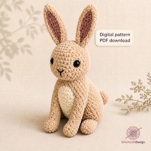 Può includere: Un coniglio all'uncinetto beige con lunghe orecchie con sezioni interne rosa, occhi neri e una macchia color crema sulla pancia. Un'etichetta rettangolare riporta Digital pattern PDF download. Il logo StitchSoftDesign è visibile in basso.