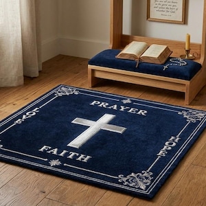 Könnte beinhalten: Ein rechteckiger marineblauer Teppich mit einem weißen Kreuz in der Mitte. Die Wörter PRAYER, FAITH, LOVE und HOPE sind in Weiß um das Kreuz herum gedruckt. Der Teppich hat einen weißen Rand mit dekorativen floralen Mustern an den Ecken.