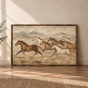 May include: A rectangular framed wall art print featuring a herd of horses galloping across a dusty, muted landscape. The scene depicts several horses in shades of brown, white, and grey, set against a backdrop of rolling hills under a cloudy sky.