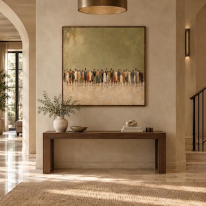 May include: A square wall art piece featuring a horizontal line of small, abstract figures in various colors against a muted olive green and beige background, framed in a thin dark wood border, displayed above a long, rectangular wooden console table.