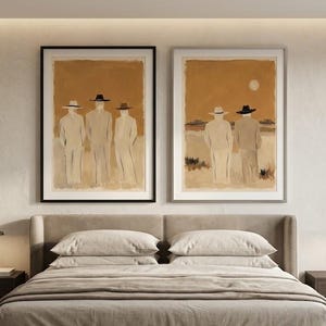 May include: Two framed wall art prints featuring abstract figures in hats against a warm, tan-coloured background. The left print shows three figures standing, while the right print depicts two figures facing a horizon with a pale sun in the sky.