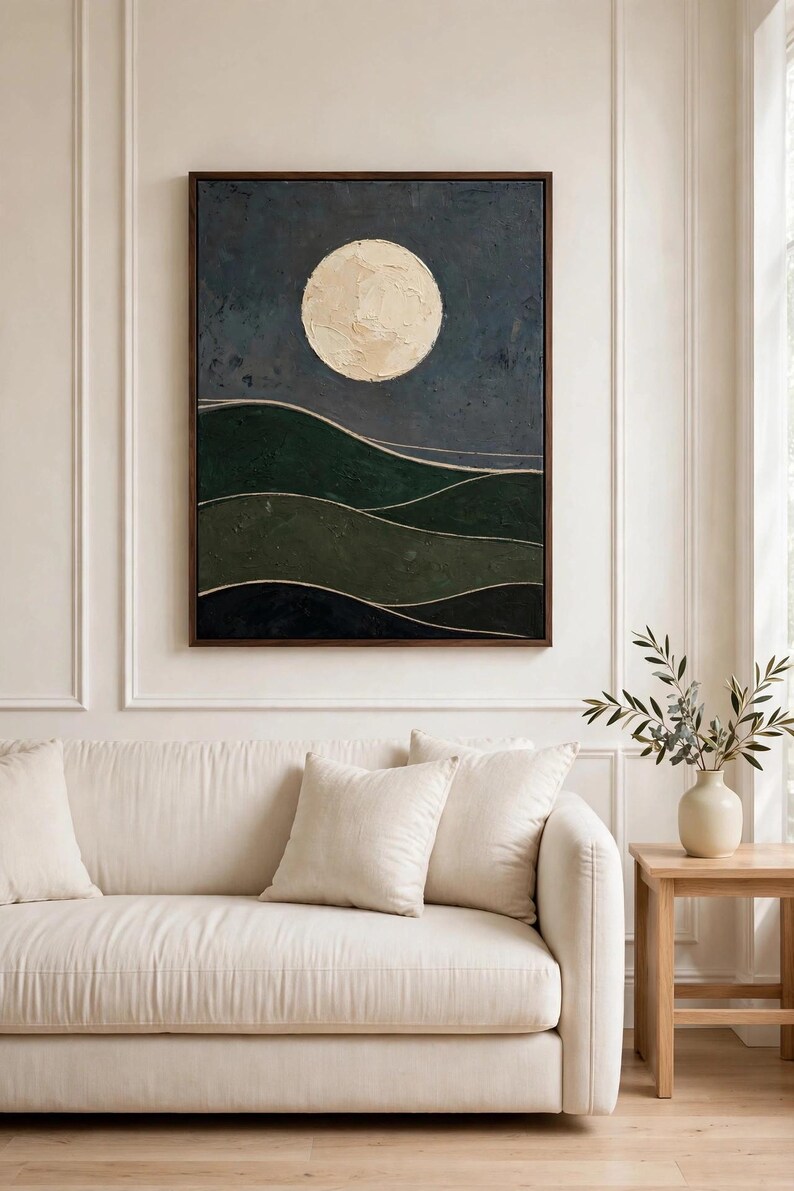 Dark green moon landscape art print framed above a cream sofa in a living room — Japandi printable wall art for a calm, modern space