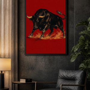 May include: A framed wall art print featuring a detailed black and gold illustration of a charging bull against a solid, vibrant red background. The bull is depicted in a dynamic stance with its head lowered and horns pointed forward.