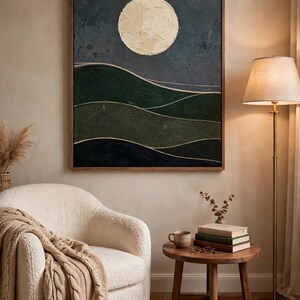 Abstract moon and hills art print above a reading chair with floor lamp — dark green Japandi wall art for a reading nook or study