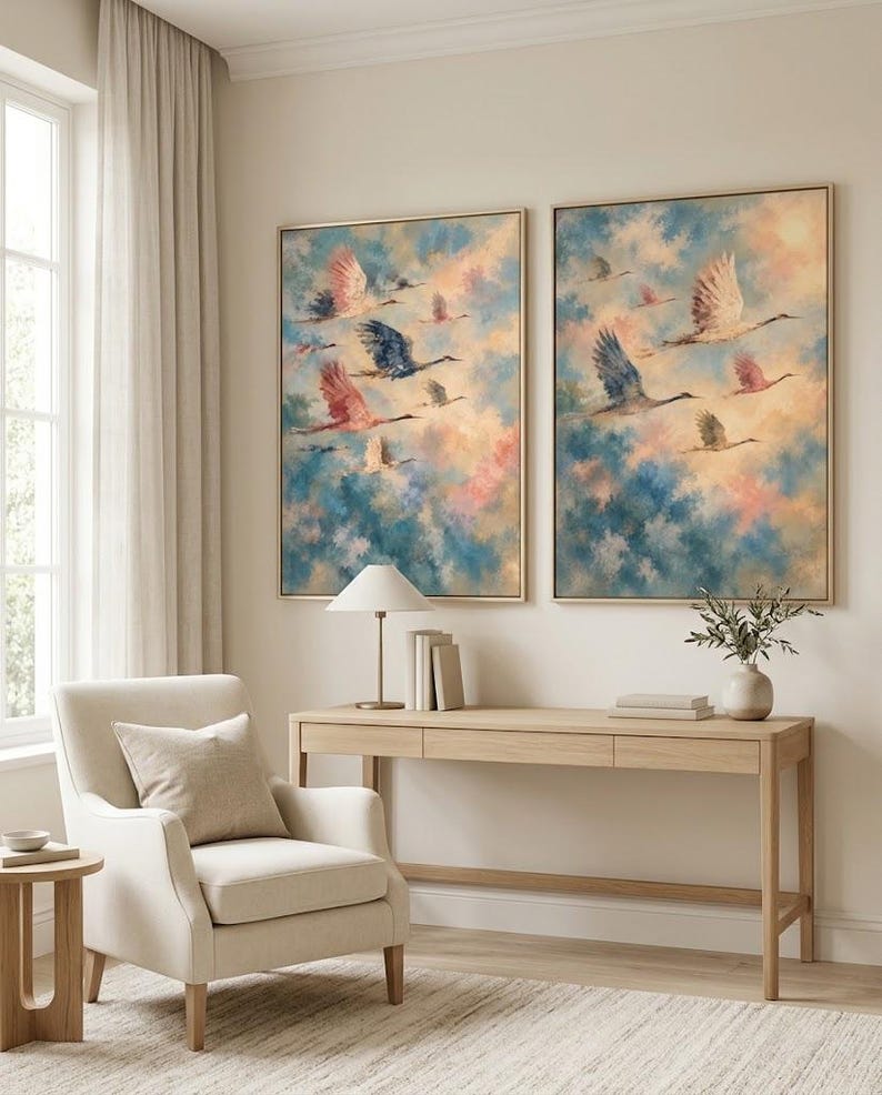 May include: Two framed rectangular wall art prints featuring a flock of birds in flight against a soft, painterly sky of blended blue, pink, and cream tones. The artwork is displayed side-by-side on a wall above a light wood console table.