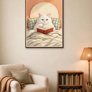 Cat reading in bed art print above a reading chair — perfect bookish wall art for a reading nook or home library
