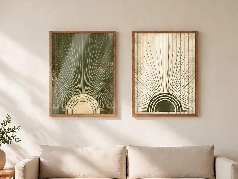 May include: Two framed wall art prints featuring a sunburst motif. The left print has a dark olive green background with a cream sun, while the right print has a cream background with an olive green sun. Both feature thin radiating lines.
