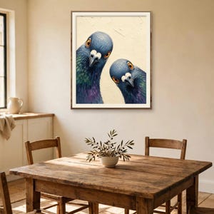 May include: A framed wall art print featuring two pigeons with iridescent blue, green, and purple neck feathers and bright orange eyes, set against a textured cream-coloured background, displayed in a simple brown wooden frame.