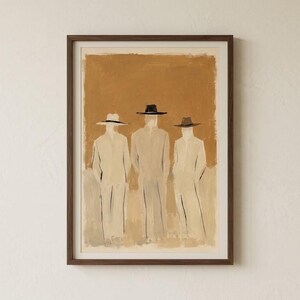 May include: A framed wall art print featuring a painting of three figures wearing wide-brimmed hats and long coats. The figures are rendered in shades of beige and cream against a solid, textured ochre-brown background within a dark wood frame.