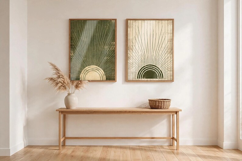 May include: Two rectangular wall art prints in wooden frames featuring a sunburst design. The left print has a dark green background with a gold sun, while the right print has a cream background with a dark green sun. Both display radiating lines.