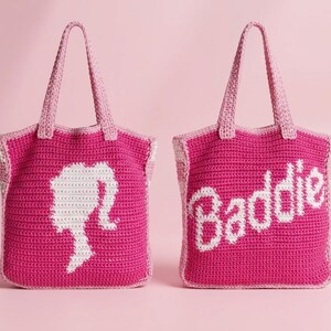 May include: Two handmade crochet tote bags in vibrant fuchsia pink with light pink handles. One bag features a white silhouette of a ponytail profile, while the other displays the white text Baddie in a cursive script font on the front.