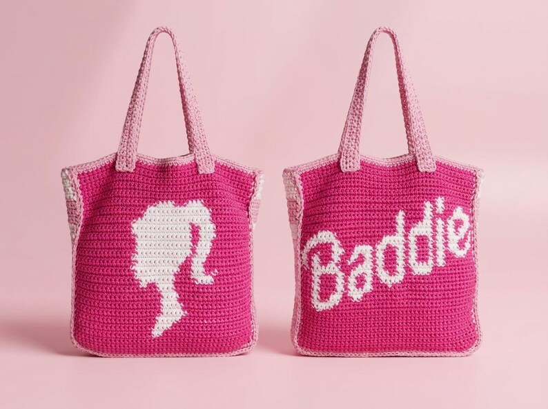 May include: Two handmade crochet tote bags in vibrant fuchsia pink with light pink handles. One bag features a white silhouette of a ponytail profile, while the other displays the white text Baddie in a cursive script font on the front.