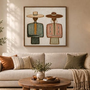 May include: A square wall art piece featuring two stylized figures wearing wide-brimmed hats and patterned tunics in shades of teal, pink, brown, and cream. The figures are depicted with simple lines against a textured off-white background.