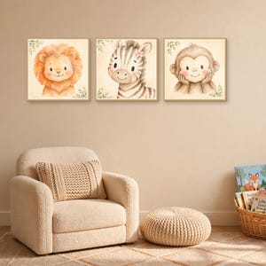 K&ouml;nnte beinhalten: Drei quadratische Wandbilder mit Aquarellillustrationen eines L&ouml;wen, eines Zebras und eines Affen. Jedes Tier ist mit weichen Z&uuml;gen dargestellt und von dezenten gr&uuml;nen Blattmotiven auf einem cremefarbenen Hintergrund umgeben.