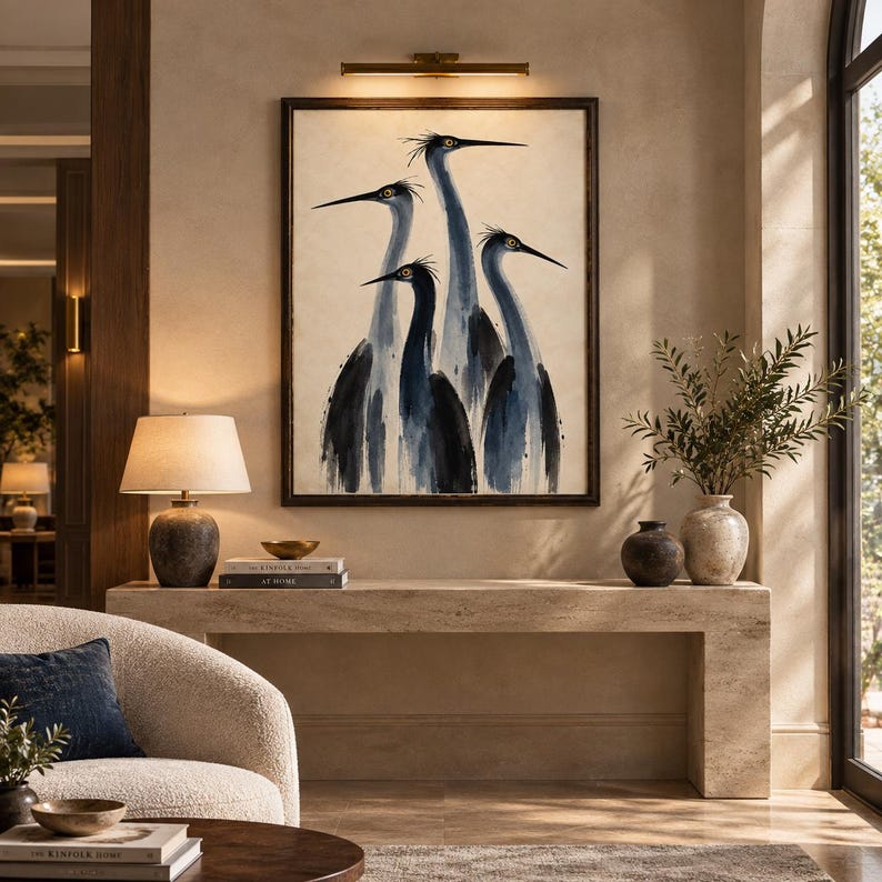 May include: A framed wall art print featuring a watercolour-style illustration of four blue herons in shades of navy and slate grey against a cream background, displayed above a long stone console table in a neutral-toned interior space.
