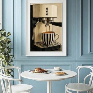 May include: A framed wall art print depicting a cream and black espresso machine brewing coffee into a black and white striped ceramic cup. The artwork features a detailed illustration of the machine with three vertical buttons and a portafilter.