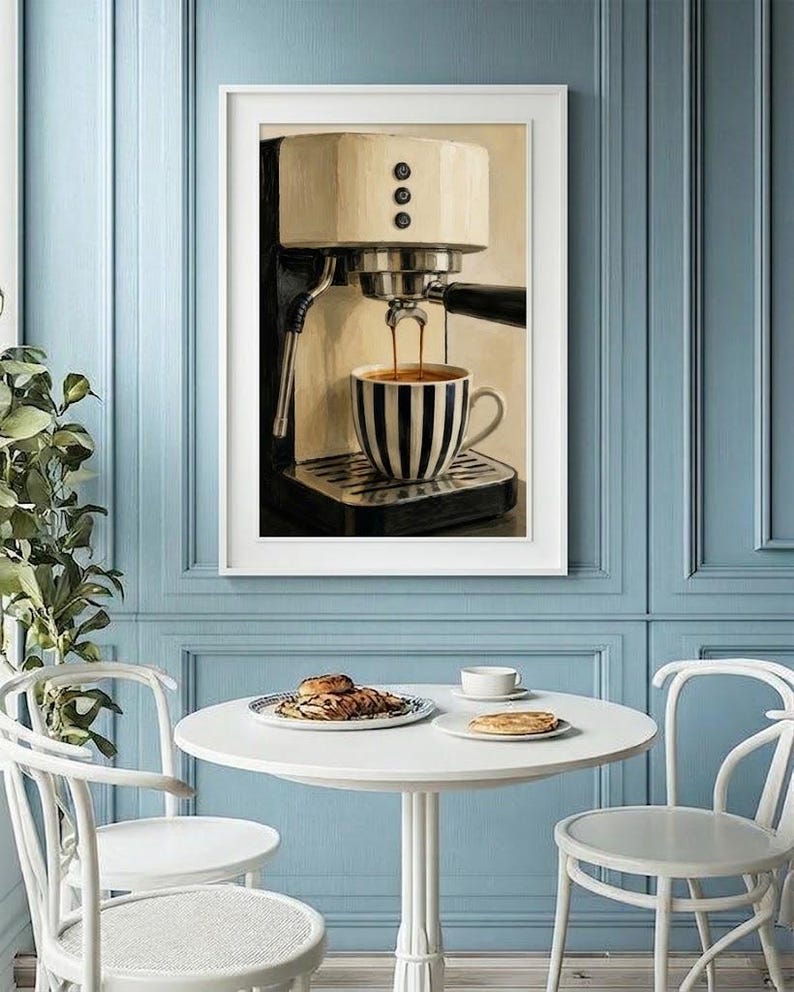 May include: A framed wall art print depicting a cream and black espresso machine brewing coffee into a black and white striped ceramic cup. The artwork features a detailed illustration of the machine with three vertical buttons and a portafilter.
