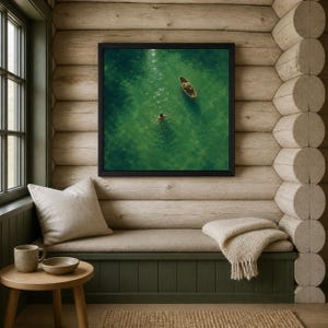 May include: A square framed wall art print featuring an aerial view of a small wooden rowboat and a person swimming in clear, vibrant green water. The artwork is displayed in a black frame, capturing a serene aquatic scene with sunlight reflections.