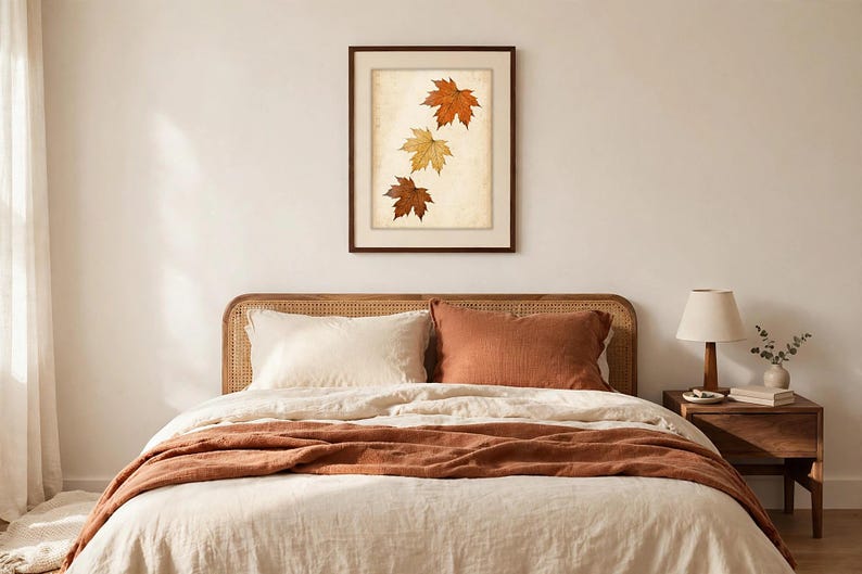 May include: A framed wall art print featuring three autumn maple leaves in shades of orange, yellow, and brown arranged vertically against a textured, off-white background. The artwork is enclosed in a simple, dark brown wooden frame.