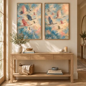 May include: Two framed rectangular wall art prints featuring a flock of birds in flight against a soft, painterly sky of blended blue, pink, and cream tones. The birds are depicted in various shades of white, pink, and dark blue with wings spread.