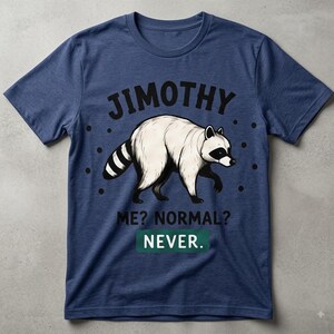 May include: A heathered navy blue short-sleeve t-shirt featuring a graphic of a white raccoon with a black mask and striped tail. The text reads JIMOTHY above the raccoon, and ME? NORMAL? NEVER. below, with NEVER inside a green rectangle.