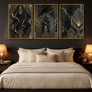 May include: A set of three rectangular wall art prints featuring black marble backgrounds with gold geometric line patterns, each encased in a thin gold frame, displayed horizontally above a bed with beige bedding and two lamps.