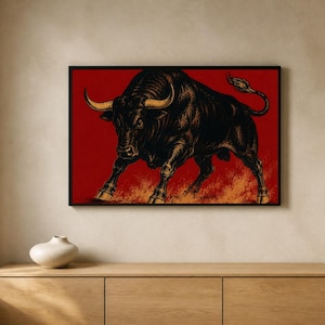 May include: A rectangular wall art print featuring a detailed black bull illustration with prominent golden horns, set against a deep red background with orange flame-like textures at the bottom, all enclosed within a thin black frame.