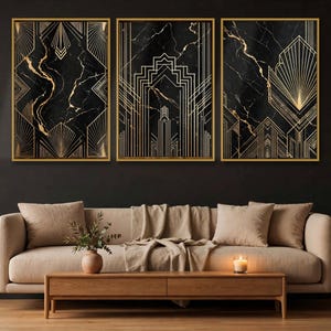 May include: A set of three rectangular wall art prints featuring black marble backgrounds with gold geometric line patterns, each encased in a thin gold frame. The prints are displayed side by side on a dark wall above a beige sofa.