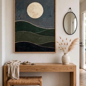 Framed Japandi landscape print with cream moon and dark green hills above a wooden console in an entryway — printable wall art