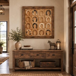 Puede incluir: Una pieza de arte mural cuadrada que presenta diecis&eacute;is herraduras dispuestas en una cuadr&iacute;cula de cuatro por cuatro sobre un fondo beige texturizado, enmarcada en madera oscura. Las herraduras var&iacute;an en color, incluyendo tonos negros, marrones y plateados.