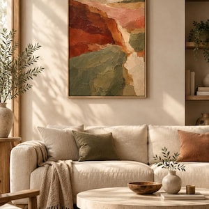 May include: A framed rectangular wall art piece featuring an abstract landscape painting with thick, textured brushstrokes in shades of deep red, burnt orange, sage green, and cream, displayed above a beige sofa in a living room setting.