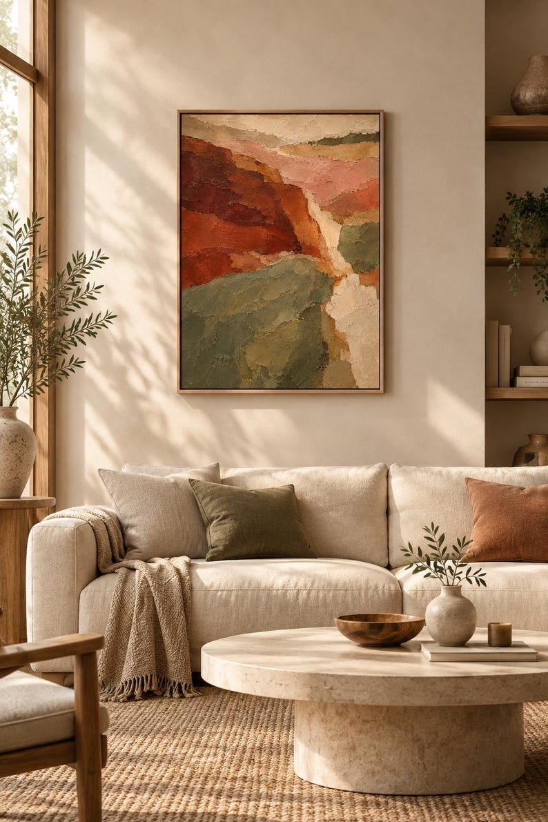 May include: A framed rectangular wall art piece featuring an abstract landscape painting with thick, textured brushstrokes in shades of deep red, burnt orange, sage green, and cream, displayed above a beige sofa in a living room setting.