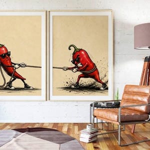 May include: Two framed wall art prints featuring a red chilli pepper character wearing sunglasses and black trainers. In the left print, the chilli pulls a rope calmly, while in the right print, the chilli pulls the rope with an angry expression.